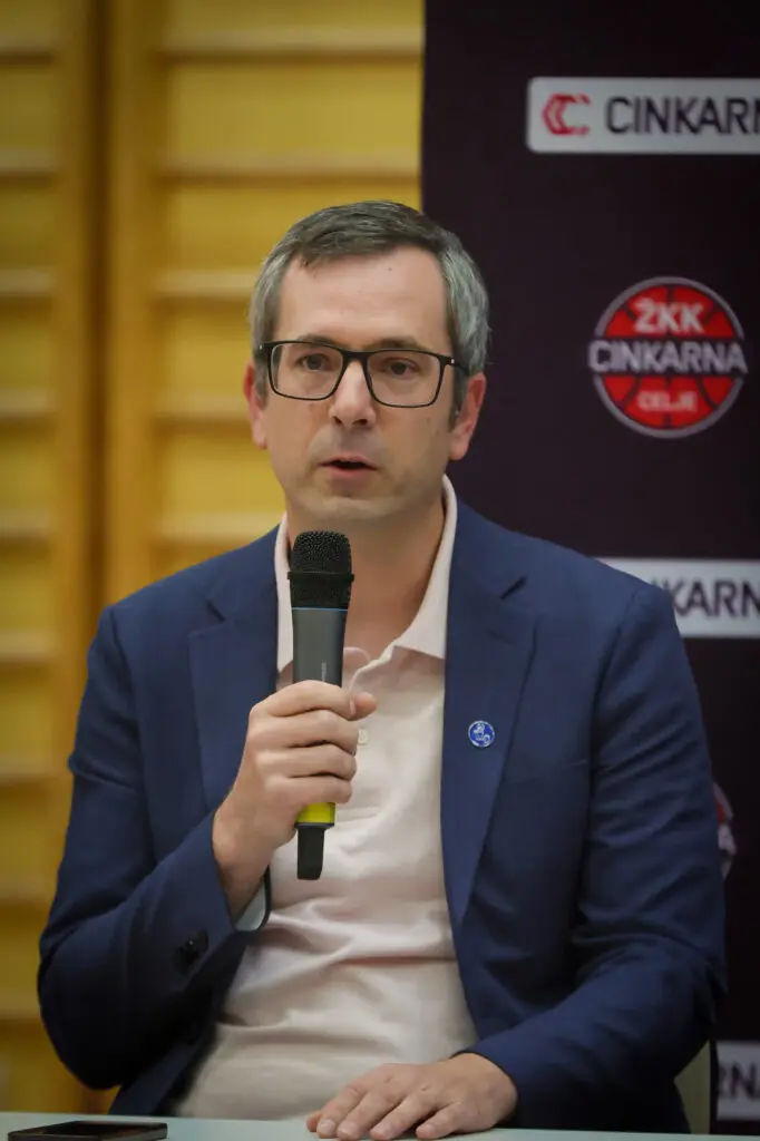 Govorec z očali in mikrofonom na predstavitvi kluba.
