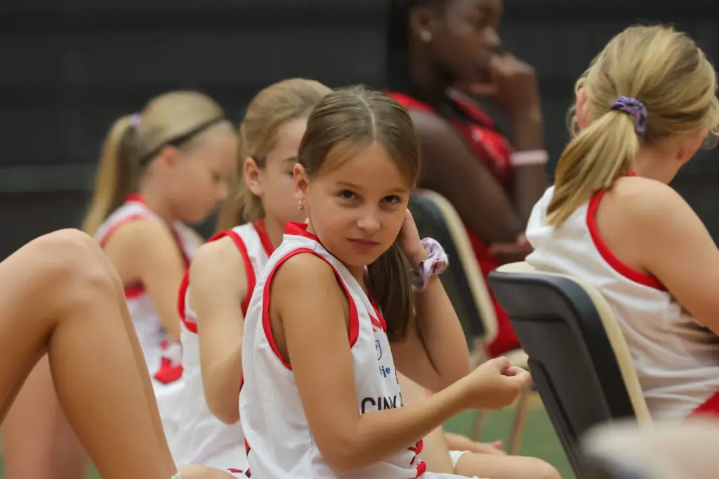 Mlada košarkarica v belem klubskem dresu med dogodkom.