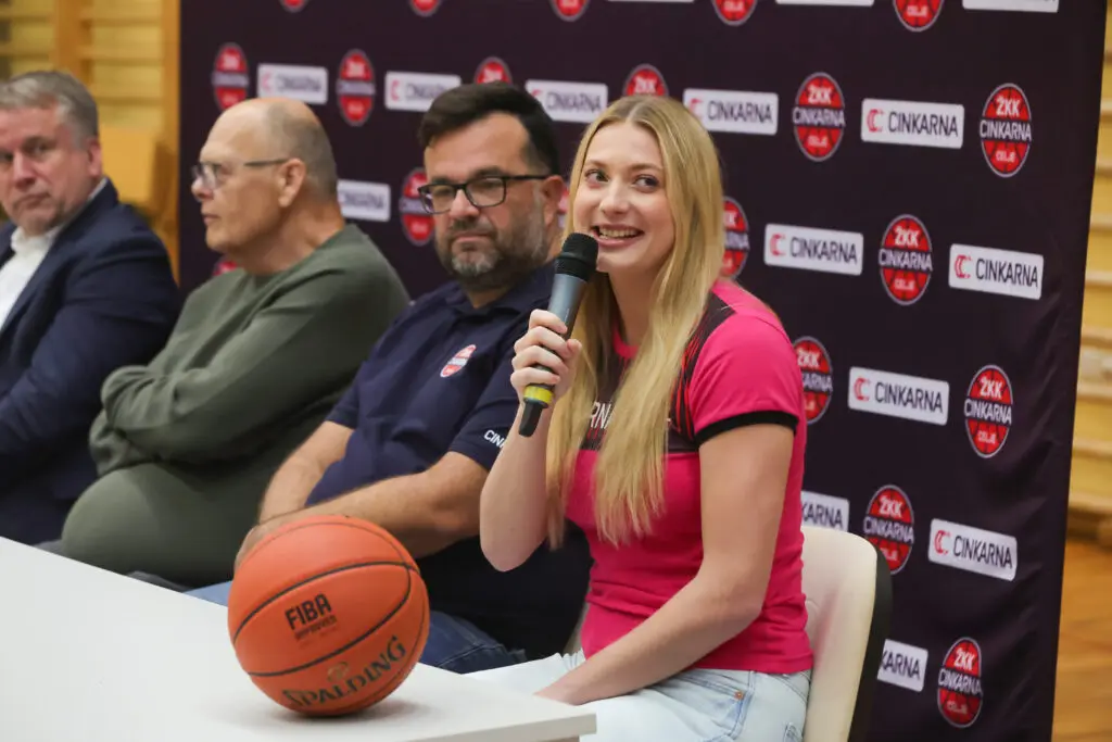 Košarkarica z mikrofonom na novinarski konferenci.