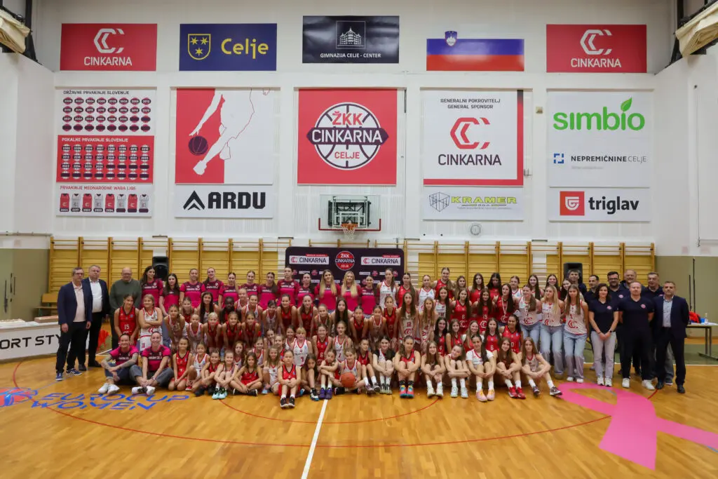 Skupinska fotografija košarkaric, strokovnega štaba in gostov v dvorani.
